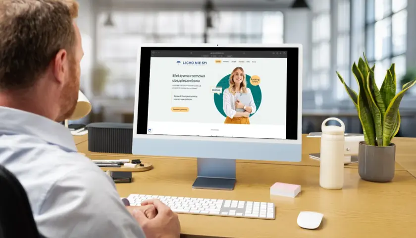 Mężczyzna pracuje przy komputerze, na ekranie którego widoczna jest strona internetowa z rankingiem ofert ubezpieczeniowych.